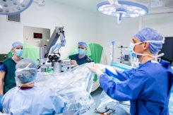 A képen egy mikroszkópos gerincműtéthez állítják be a műtőssegédek a speciális, a műtéti helyről a sebész számára felnagyított képet adó műszert.