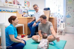 Dr. Nádor Csaba neonatológus és Bajnok Ildikó a Szülészeti és Nőgyógyászati Klinika koraszülött osztályához (PIC) tartozó ambulancián épp felmérik, hogy mennyit fejlődött az elmúlt hónapban Olívia. A kislány méhen belüli fejlődéselmaradás miatt három hónappal korábban, és extrém kis súllyal született, majd 74 napot töltött a kórházban, és számos nehézséget leküzdve tért haza. Édesanyja számára óriási támogatást és megnyugvást jelentett az először egy, majd 2-3 havi rendszerességű konduktori és szakorvosi konzultáció. „Több, mint húsz éve indult ez a fajta szakmai együttműködés, ami akkoriban még egyedülálló volt a hazai gyakorlatban” – mondja Bajnok Ildikó.